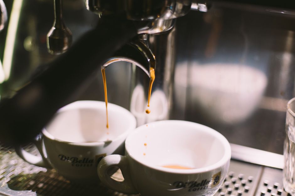 Close-up of espresso dripping into white cups from a coffee machine, creating a cozy café atmosphere.
