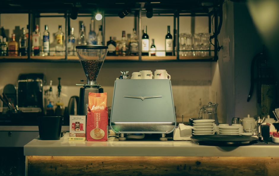 A warm and cozy cafe interior showcasing an espresso machine and bar area with coffee supplies.